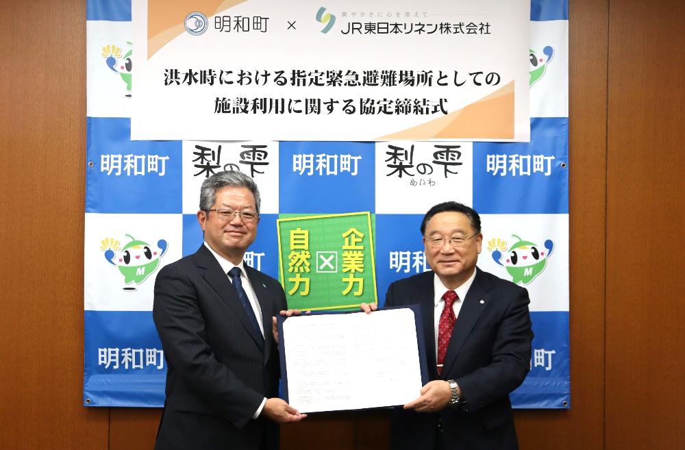 町長とJR東日本リネン株式会社の社長が協定書を手に微笑んでいる