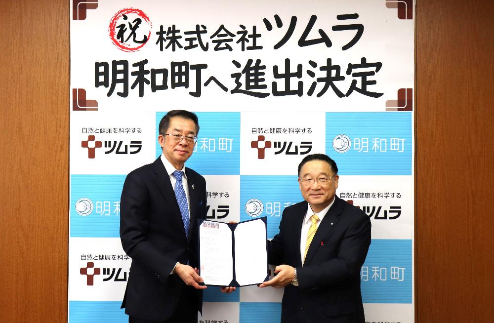 ツムラの社長と明和町長が協定書をもって微笑んでいる様子