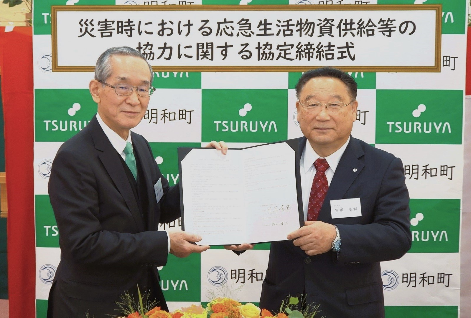 ツルヤの社長と明和町の町長が協定書を持って微笑んでいる様子