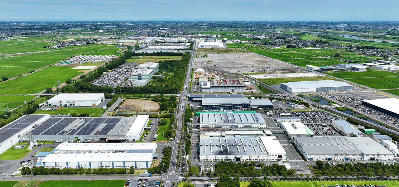明和町の空撮画像。工業団地の工場が林立し、遠くに畑や利根川が見える