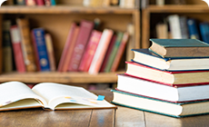 本が4冊積み重なっており、その左側に1冊の本が開かれている