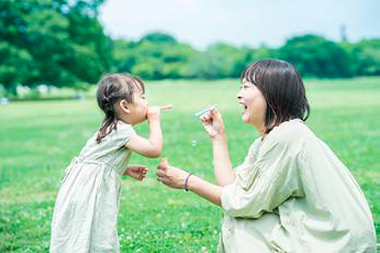 お母さんと女の子が対面でシャボン玉を吹いている様子。