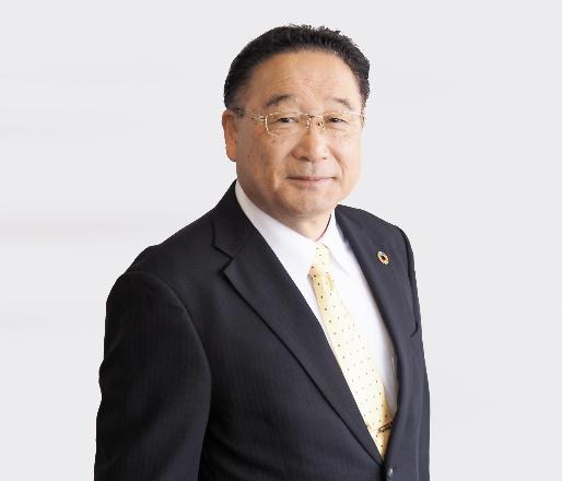 明和町の冨塚町長が、紺色のスーツを着て微笑んでいる